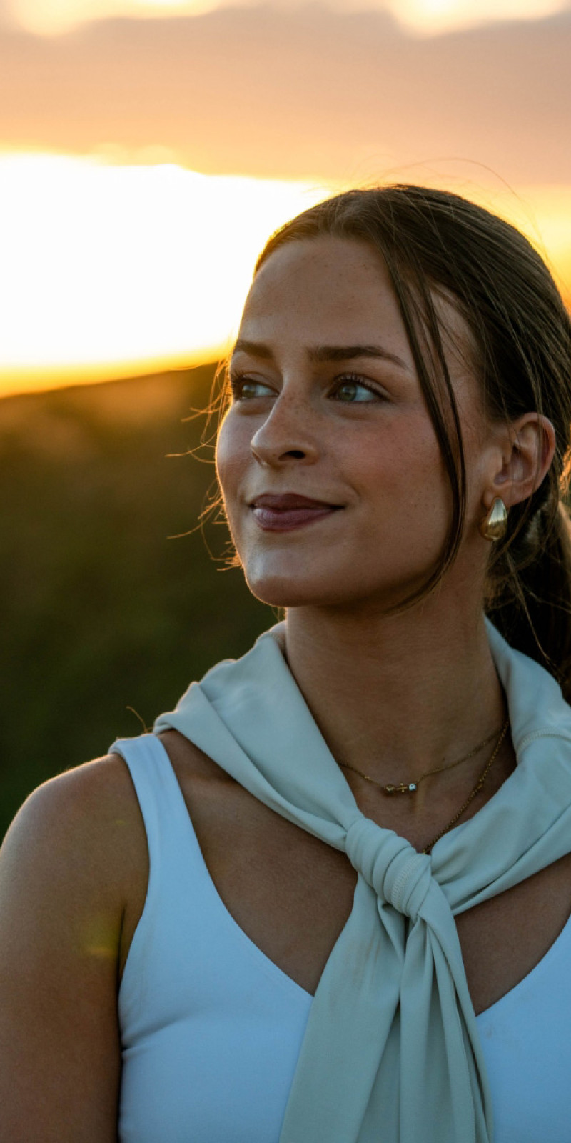 A woman standing on a hillside at sunset